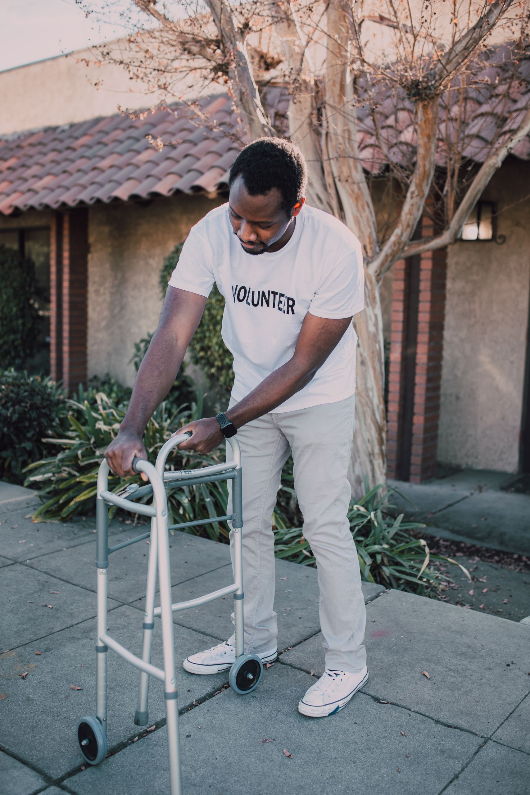 African American volunteer preparing a walker outside a house, showing community service.